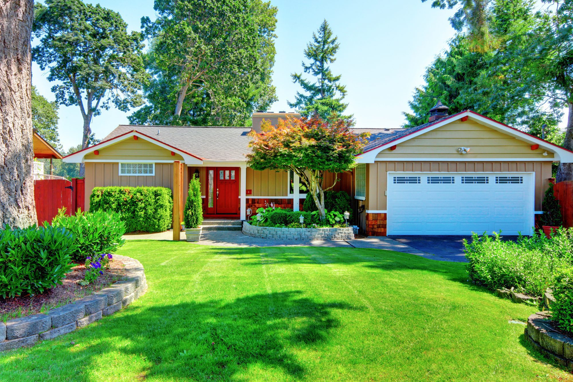 cute small rambler house with red door and white garage door.