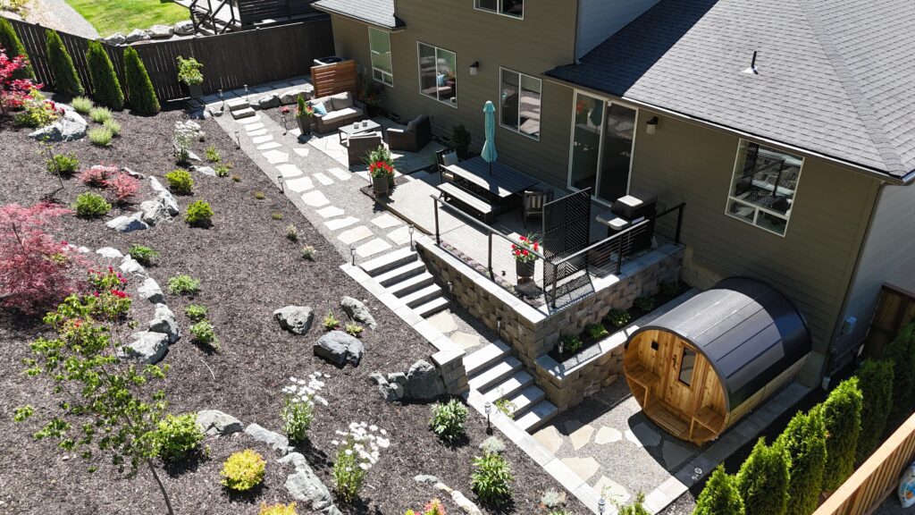 Completed outdoor living space in Bellingham with new patio, retaining walls, drainage, and custom sauna by Puget Construction & Landscape
